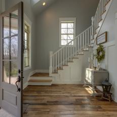 Entryway With Rustic Hardwood Floor and White Banister Stairs