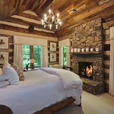 Log Cabin Bedroom With Wood Ceiling and Stone Fireplace