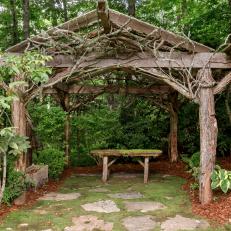 Rustic Arbor With Tree Trunk Posts and Mossy Bench