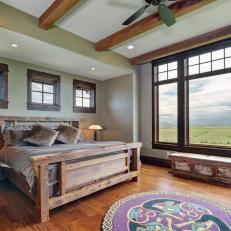 Bedroom With Ceiling Beams, Large Windows and Rustic Bed