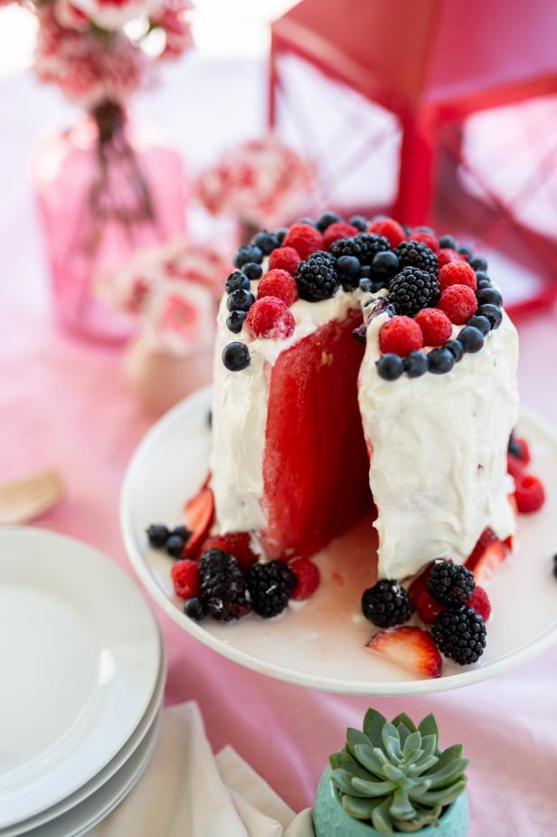 A Watermelon Cake With a Slice Cut Out and Berries On Top