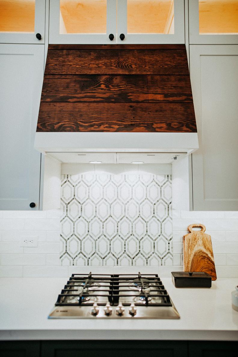 Close Up View Of Shiplap Range Hood And Storage Cabinets Above
