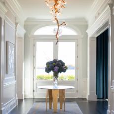 Entryway With Artistic Ceiling Light and Table With Flowers
