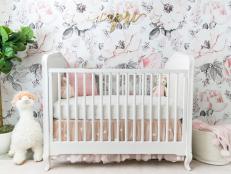 Close Up Of Crib In Front Of Floral Pink Accent Wallpaper