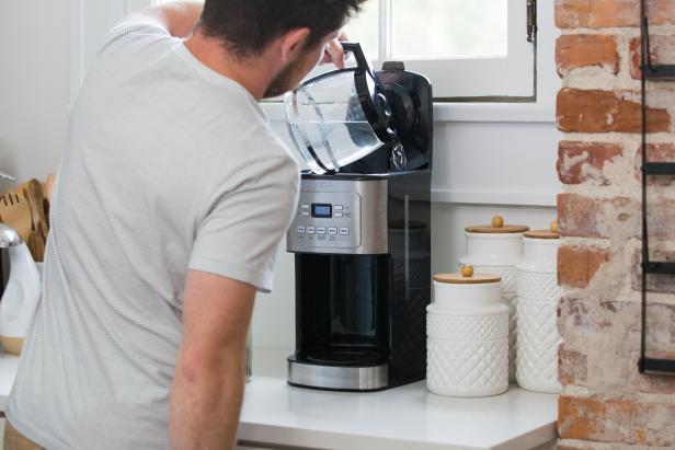 A Coffeemaker is Filled With Water by a Man