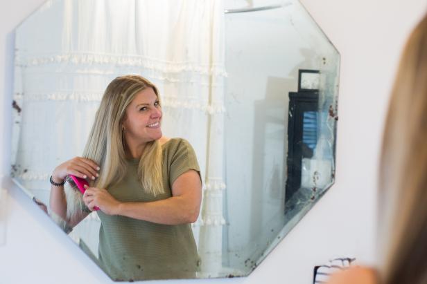 Lady Looking in Mirror Brushing Hair in White Bathroom