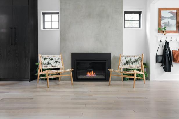 Concrete Fireplace With Wood-Framed Chairs and Windows on Either Side