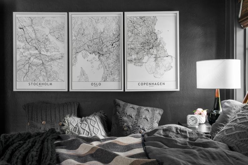 White-Framed Maps on Black Bedroom Wall