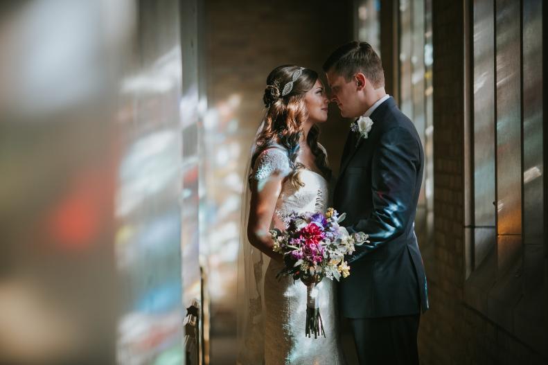 Bride and groom in front of church's stained glass window