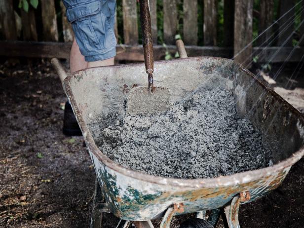 Using a wheelbarrow and garden hoe, mix the concrete according to instructions on the bag.