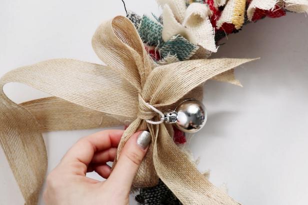 Cut a length of burlap ribbon and thread it through the wreath. Use hot glue to glue it closed. Tie a bow using the ribbon and glue it onto the wreath.