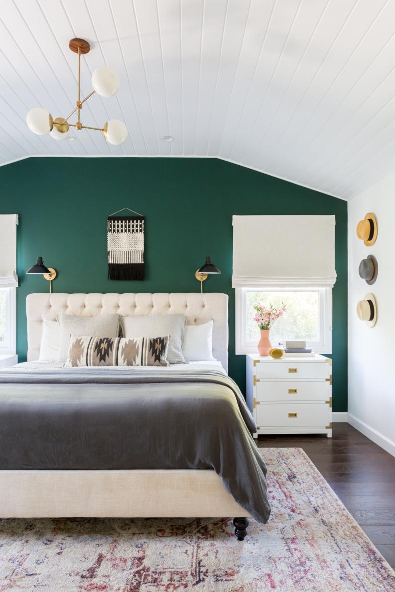 Vaulted Ceilings In Bedroom With Tufted Headboard And Hats On Wall