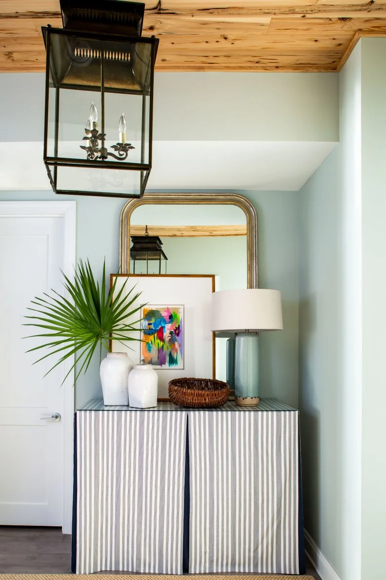 Cabinet With Fabric Curtains In Entry With Mirror And Vases On Top