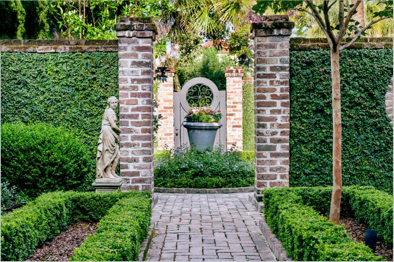 A brick pathway leads from the main garden room to a smaller ancillary room demarcated by brick walls featuring carefully manicured creeping fig.
