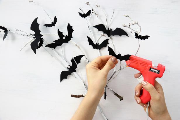 Gently fold the bat shapes in half and hot glue them onto the branches.