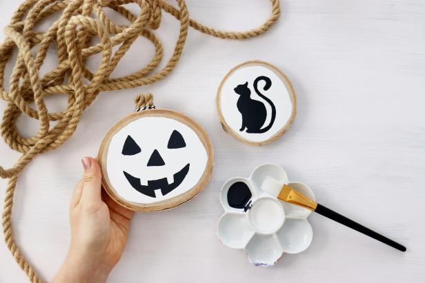 We painted cat and pumpkin silhouettes onto these wood rounds for a chic farmhouse Halloween display.