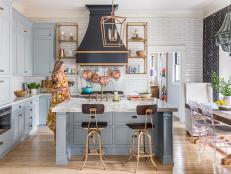“I wanted a kitchen that felt sophisticated, to fit with the original look of the house,” says Brittany. A majestic powder-coated-wood range hood in black and gold by APF, Inc. became the centerpiece, contrasted with custom-color gray blue cabinets and luxe marble countertops. Gold-toned shelves echo the hood. “Even cooking spaghetti feels fancy in this kitchen,” says Brittany.