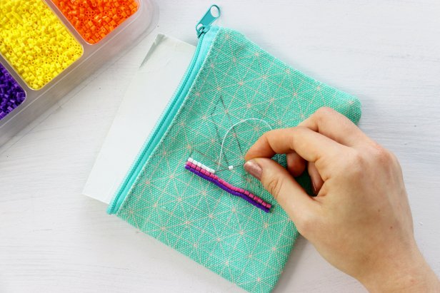 lace a piece of cardstock inside the pouch so you don’t sew through the other side. Thread the needle and begin sewing on the mini Perler beads.