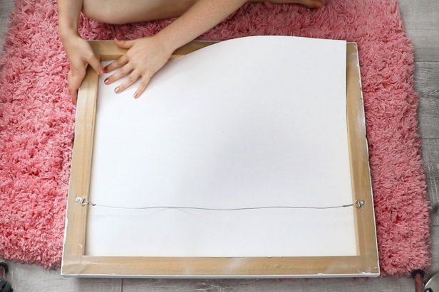 Start with a piece of canvas wall art. Cut a piece of poster board to fit inside the wood frame to give the canvas more structure and prevent your papers from showing through.