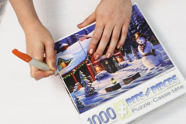 Next, use a craft knife or scissors to cut the picture from the front of the jigsaw puzzle box.