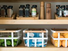 While opaque baskets are ideal for all the clutterables you need access to but don't want to see, see-through baskets made of metal or mesh allow everything inside to double as decoration. Here, limes and oranges used on an everyday basis keep organic color and texture on display when the door is open.