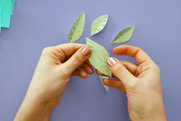 Make additional leaves by scoring a line down a piece of cardstock. Fold it in half and cut half of a leaf shape down the fold. Open them up to reveal your leaves.