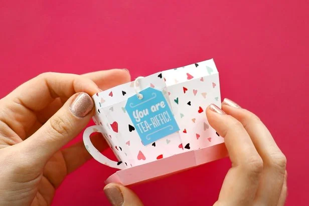 Print Page 3 of the pattern and cut out one tea bag shape. Punch a hole in the top and tape a piece of string to the back of the teabag. Tape the other end of the string to the inside of the cup.