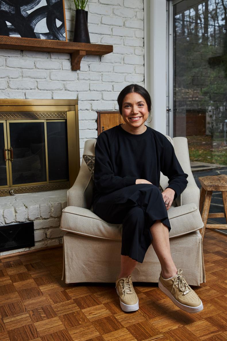 Woman Sits In Comfy Chair In Living Room With Fireplace