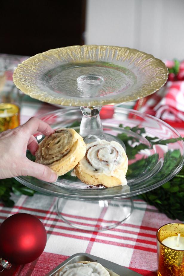Fill the bottom tier with cinnamon rolls. Tuck pieces of food-safe greenery (faux or fresh) and Christmas ornaments around the cinnamon rolls.