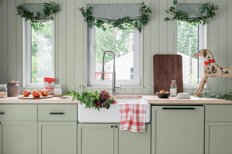 A mix of traditional and farmhouse antiques were used to furnish the space and also jazz it up with holiday flair. Flexible faux branches attached with simple clothespins add texture along the Roman shades.