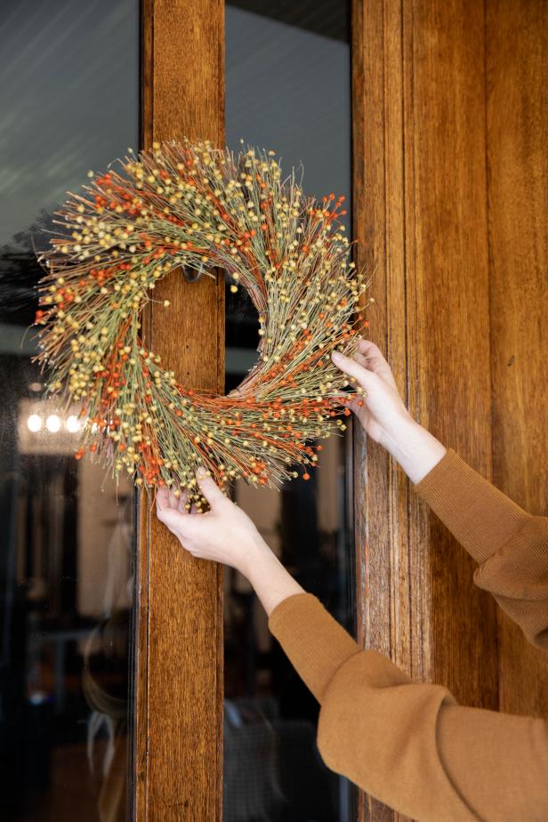 A Woman Placing a Fall Wreath on a Door