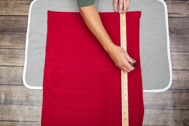This yard stick is being used to measure and mark dots along red jersey fabric. Scissors will be used to cut slits at each mark to thread red ribbon through for a Little Red Riding Hood Halloween costume.