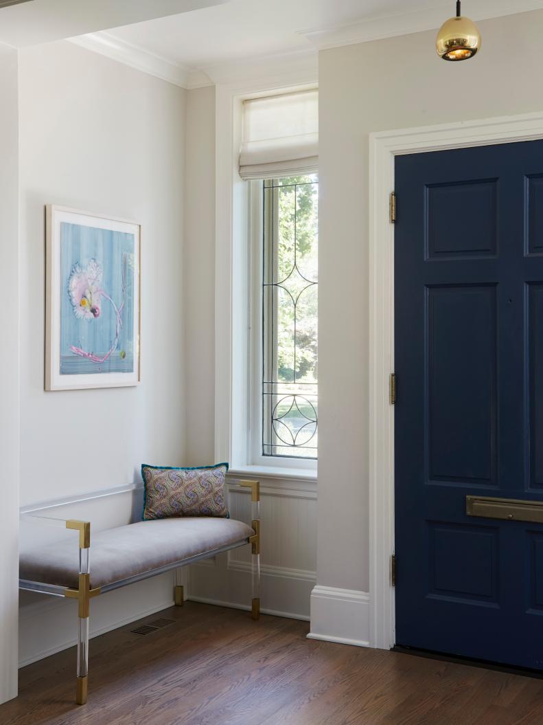 This entrance includes a blue door and lucite bench.