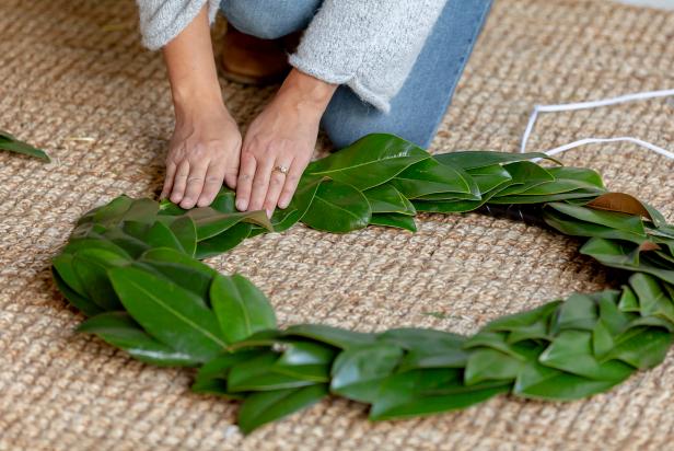 These magnolia leaves are pressed onto a hula hoop frame and attached using hot glue. The oversized wreath DIY is easy and affordable.