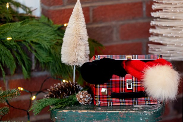 This vintage lunchbox makes for the perfect festive container to hold cozy winter hats and mittens. The lunchbox is placed on a front porch for easy access when it gets cold. Decorations are placed around the festive box, making it look like part of the porch's decor.