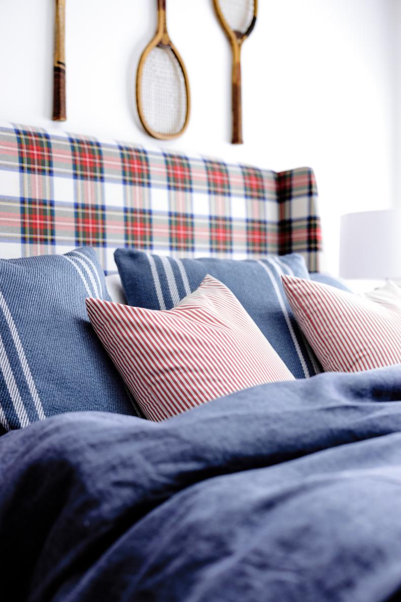 Plaid upholstered bed with red striped accent pillows and blue bedding