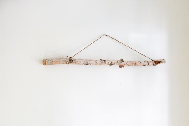 This birch limb has been secured to the wall using twine to be used to hold bunches of free greenery for a Christmas tree wall hanging.