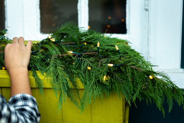 Foraged greenery is placed in a window box along with battery-powered outdoor Christmas lights to create a beautiful display for the coming season.