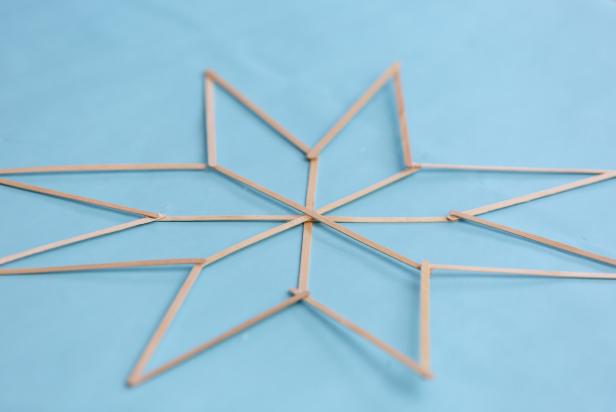 This star decoration is made using coffee stir sticks that have been glued together using hot glue. The minimalist decor will be strung up in a window for display.