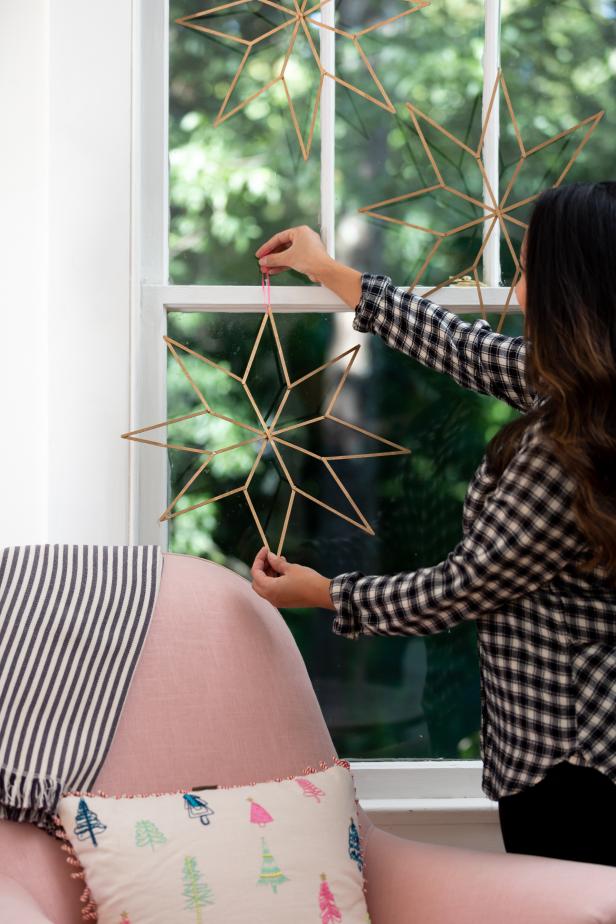 This Christmas star decoration is made with coffee stirrers and draped from a window using ribbon and nails. The stirrers are secured together using hot glue to create the star shape and then painted using metallic gold spray paint. The minimalistic star fits in with any holiday decor.