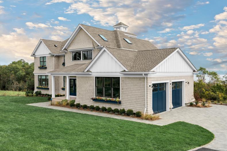 A curved driveway with durable natural stone-look pavers leads to the front doors of the versatile garage, with space inside for working on home projects, and lounge seating for casual indoor/outdoor entertaining. 