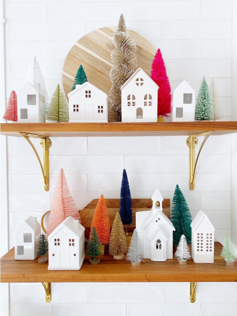 Bright evergreen trees pop behind tiny white houses on designer Jo Gick's festive shelving. She strayed from the classic Christmas color scheme, instead weaving pink, orange, and even navy, into her decorations.