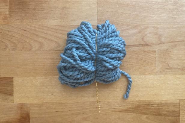 Using scissors, cut the loops on both sides just like you would to create a pom-pom. Next, give the yarn a trim so that it resembles a tree, cutting a triangular shape from bottom to top.