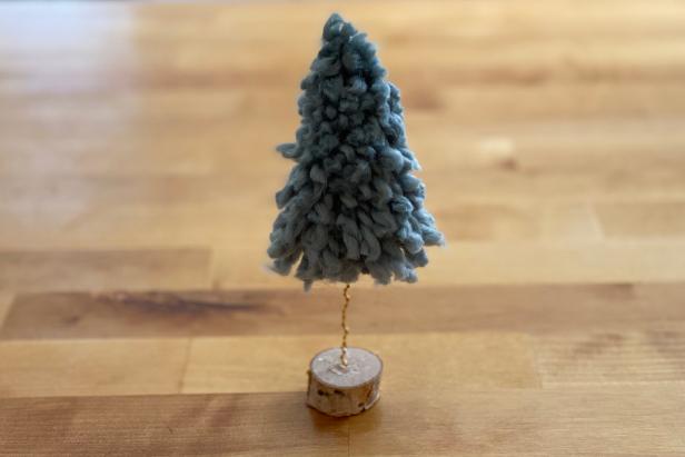 HGTV Handmade’s Danielle Boaz shares step-by-step instructions for easy yarn Christmas trees that take minutes to create. To make your own, you will need several bundles of yarn in festive colors, pieces of cardboard, round wooden discs, wooden skewers, an adhesive dot roller, floral cone, jewelry wire, electric drill with small drill bit and a low-temp hot glue gun.