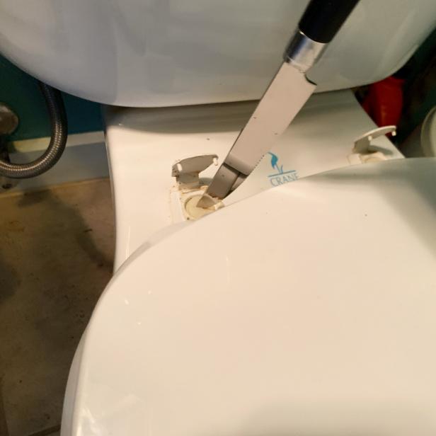 In a pinch, HGTV editor Jessica Yonker used a butter knife to remove her toilet seat while installing the TUSHY Classic bidet seat attachment.