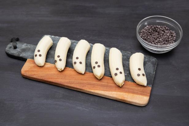 These banana ghosts have been made by cutting bananas in half and poking chocolate chip ghost faces into the tapered ends. The Halloween snack is an effortless addition to any Halloween party as it only takes bananas, a knife and chocolate chips to create quickly.