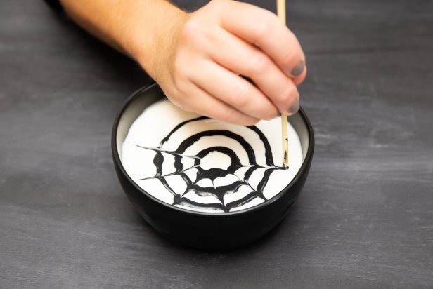 This Halloween-themed fruit dip utilized black cookie icing to create spiderweb. The web is created by making concentric circles of cookie icing, then dragging outward from the center using a wooden skewer.