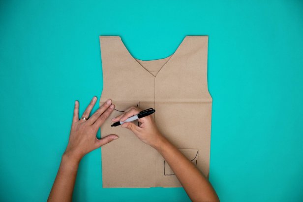 This fisherman's vest Halloween costume is made from paper bags. Pocket details are being added with magic marker.
