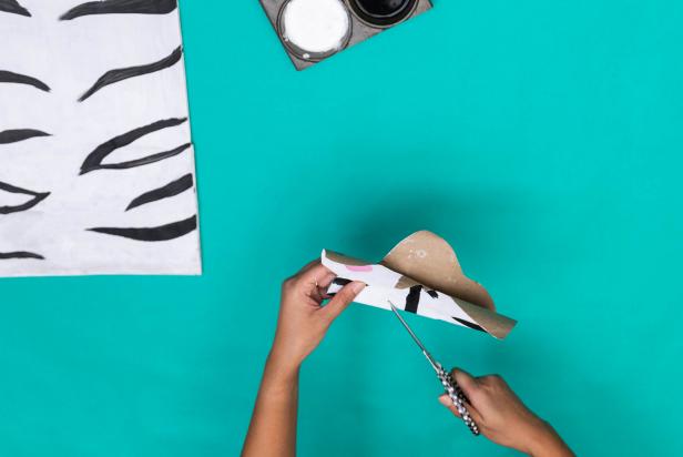 This paper bag zebra mask is being cut out and painted to look like a realistic zebra. The inexpensive DIY is a perfect homemade Halloween costume option.