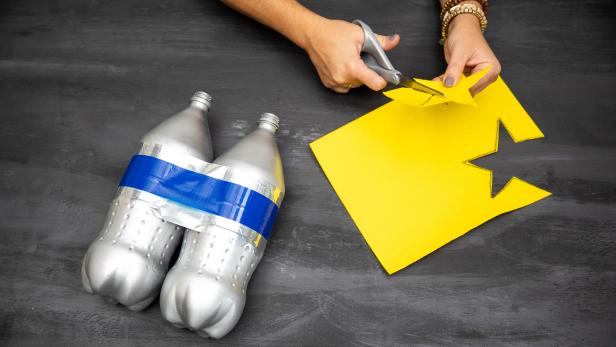 This yellow felt star is being cut to stick on a DIY jetpack for an astronaut Halloween costume. Stick-on felt is used to stick the star directly to the painted 2-liter jetpack.